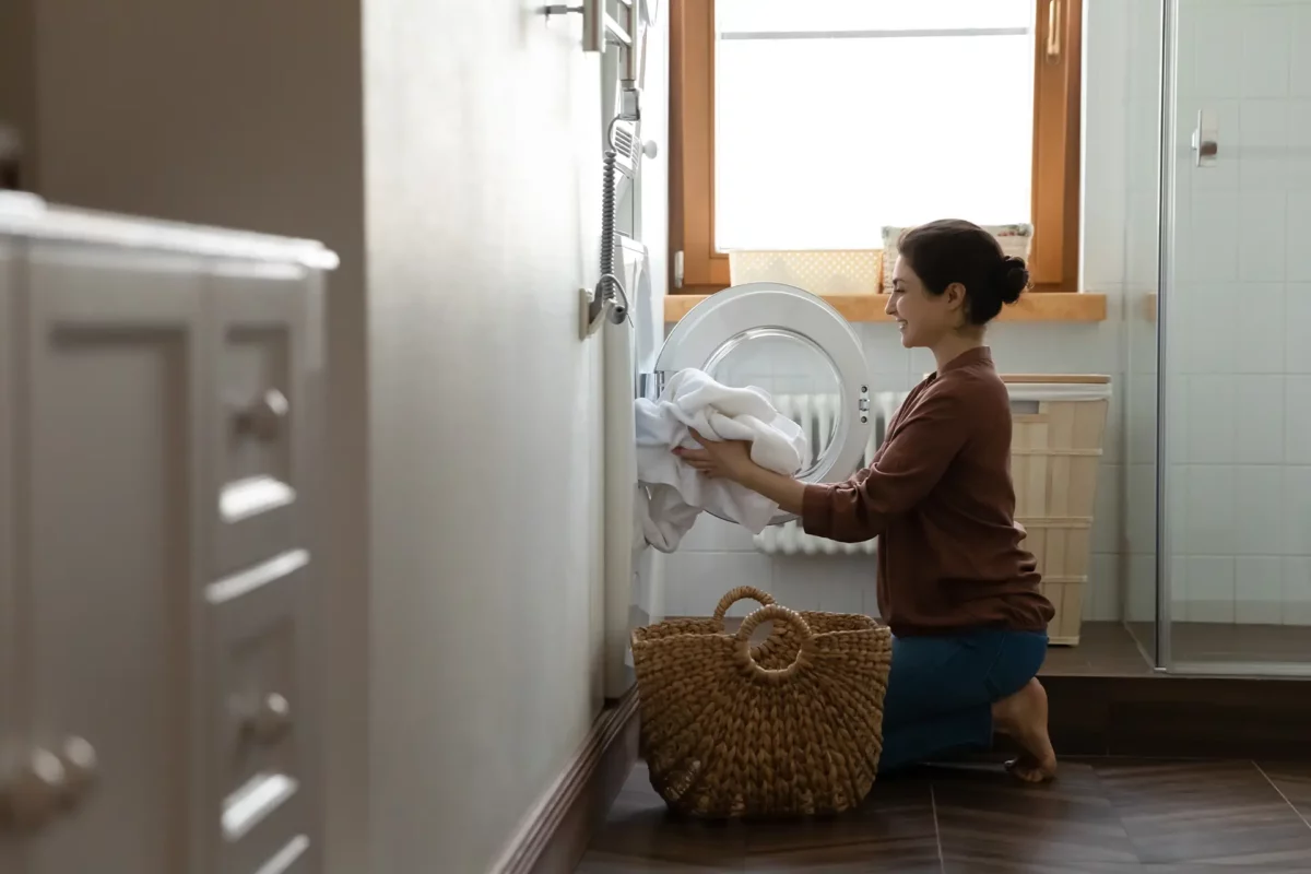 Une jeune femme en train de sortir du linge d'une machine à laver