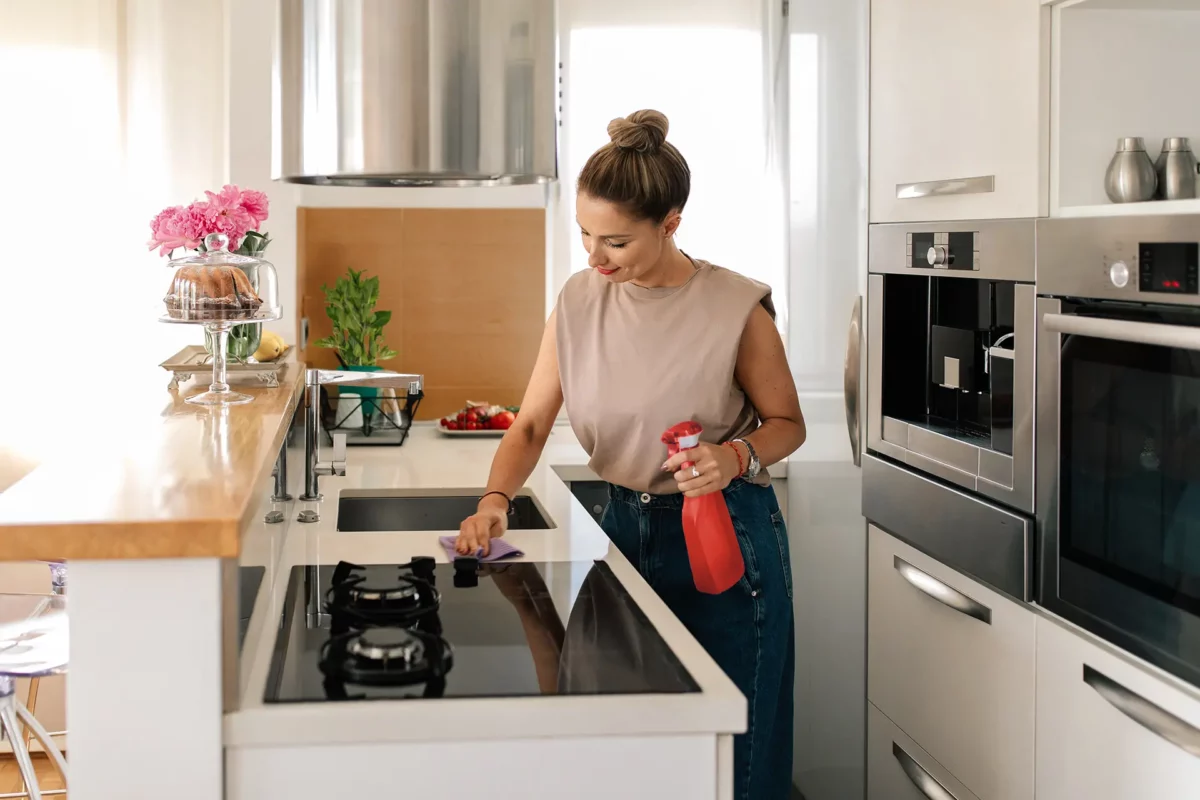 Une jeune femme en train de nettoyer une plaque de cuisson