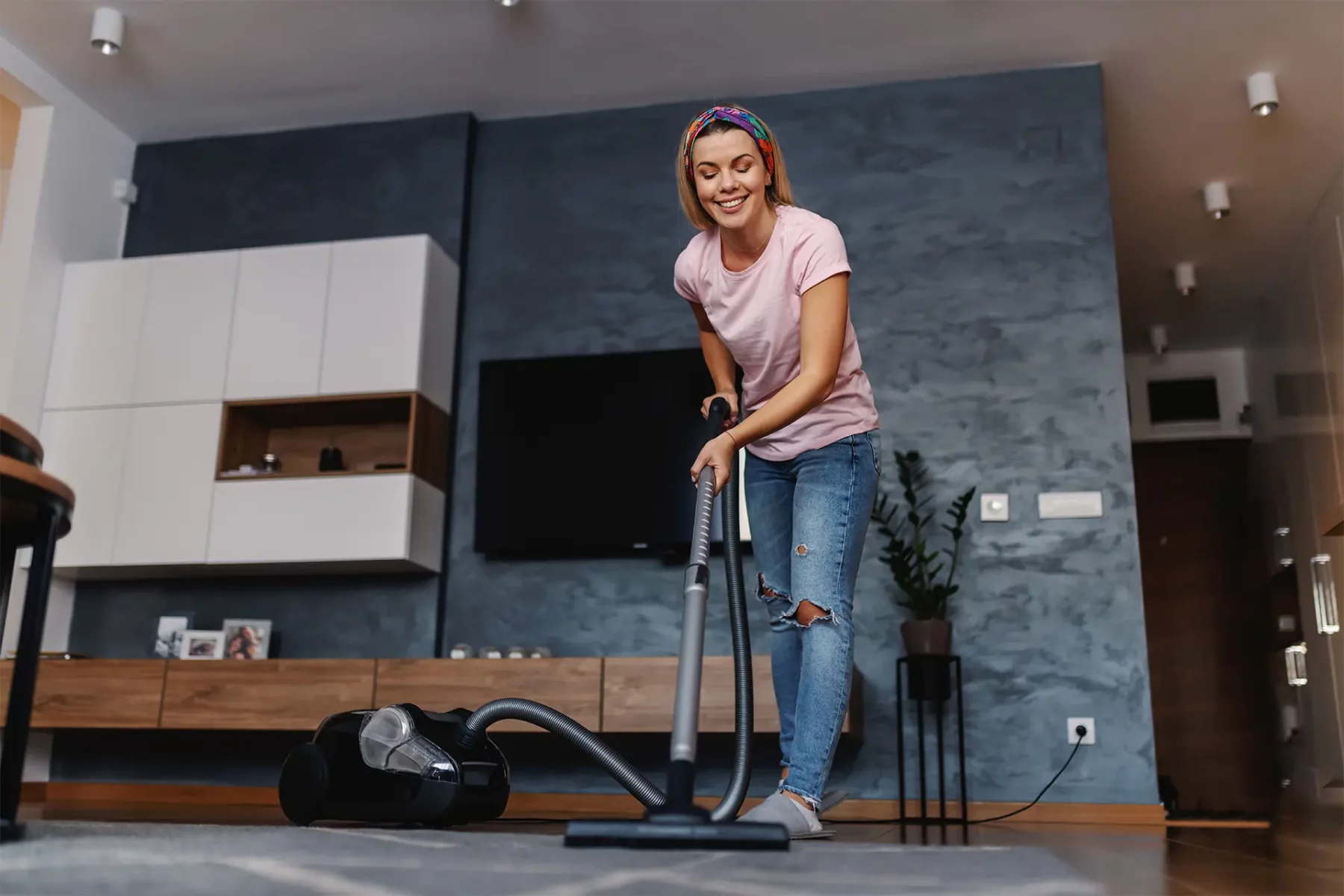 Une jeune femme en train de passer l'aspirateur