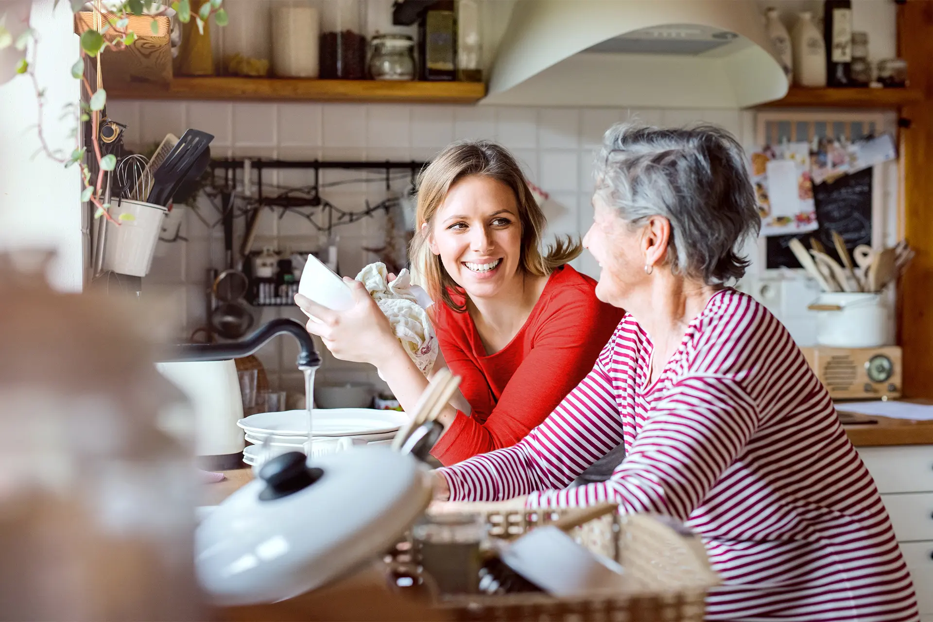 Une femme qui fait la vaisselle tout en discutant avec une autre femme