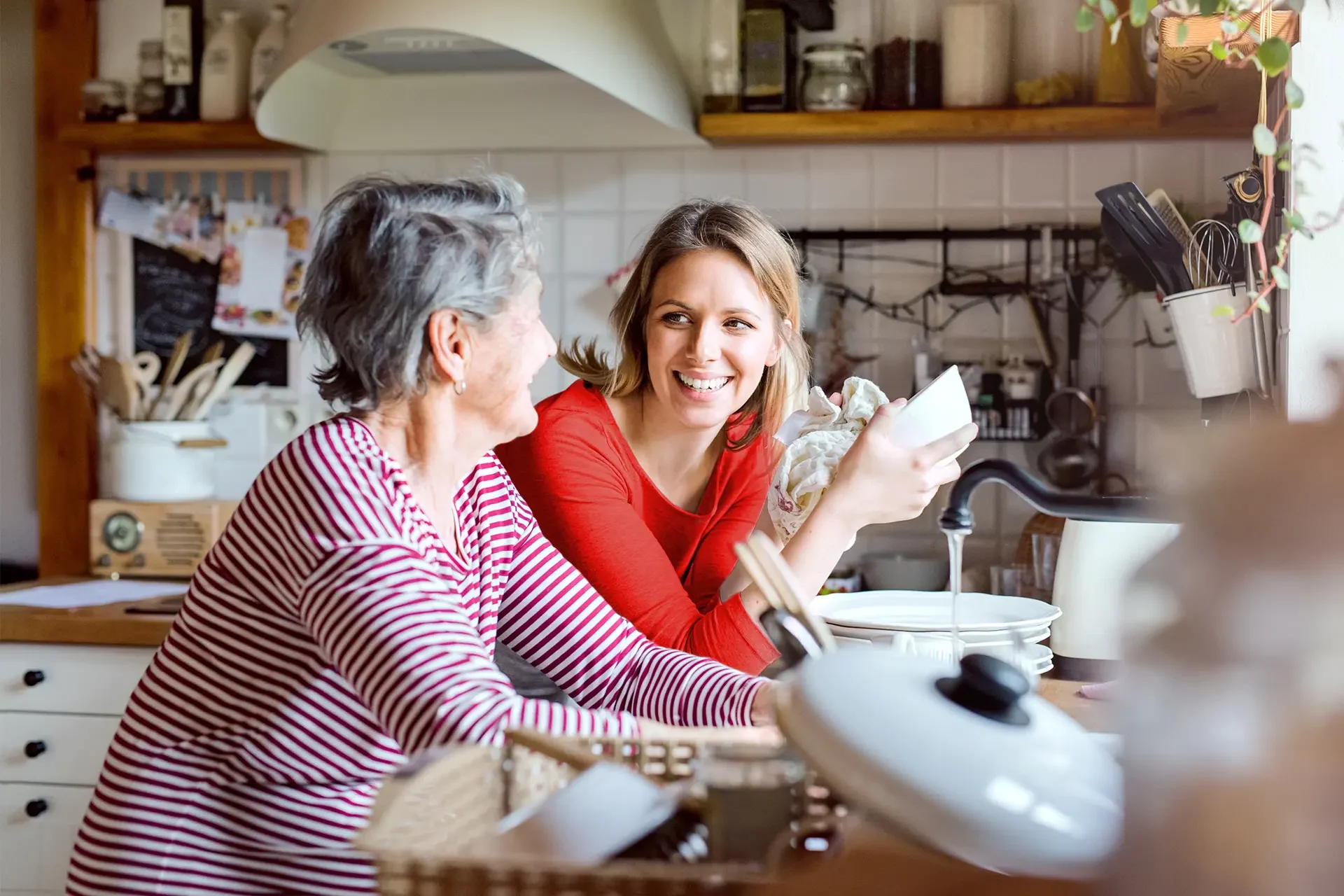 Jeune femme faisant la vaisselle discutant avec une femme âgée