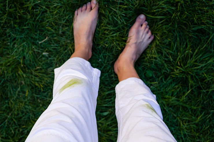 personne ayant une tache d'herbe sur son pantalon blanc