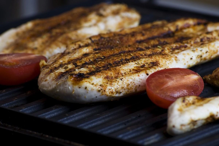 des aliments entrain de cuire sur une plancha en inox