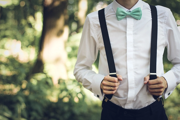 Un homme portant sur lui une chemise, des bretelles et un nœud papillon