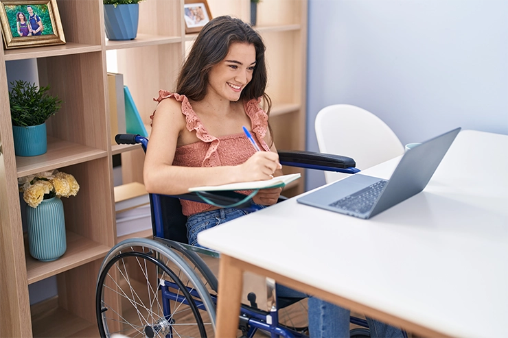 Photo d'une femme en situation de handicap prenant des notes devant un ordinateur